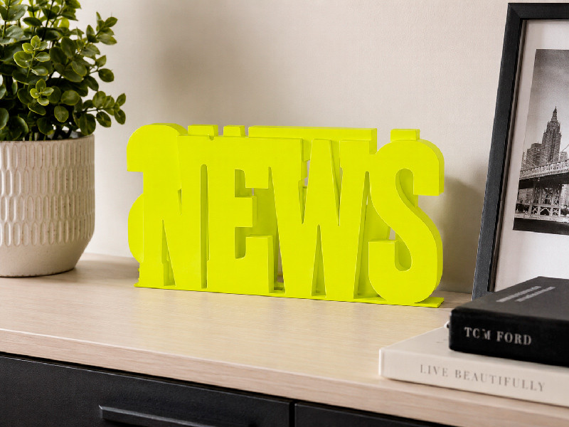 Revistero News verde metálico decorativo sobre el mueble
