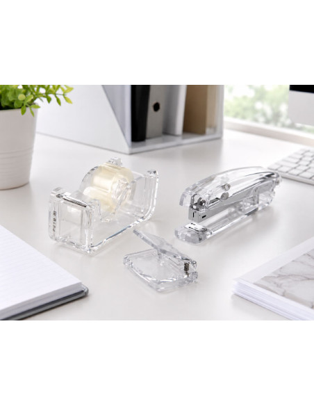 Set de escritorio acrilico transparente con grapadora dispensador de celo y taladradora en mesa de trabajo.