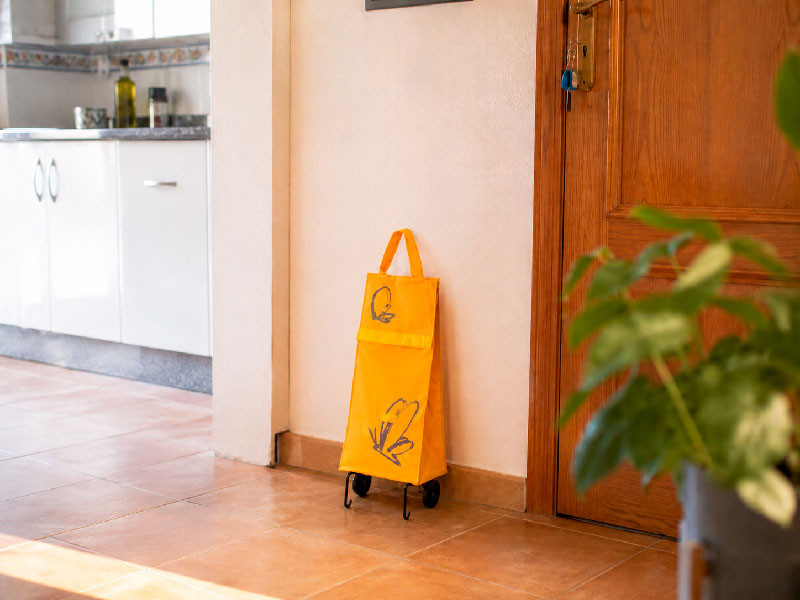 Carrito de la compra plegable color naranja en una cocina moderna.