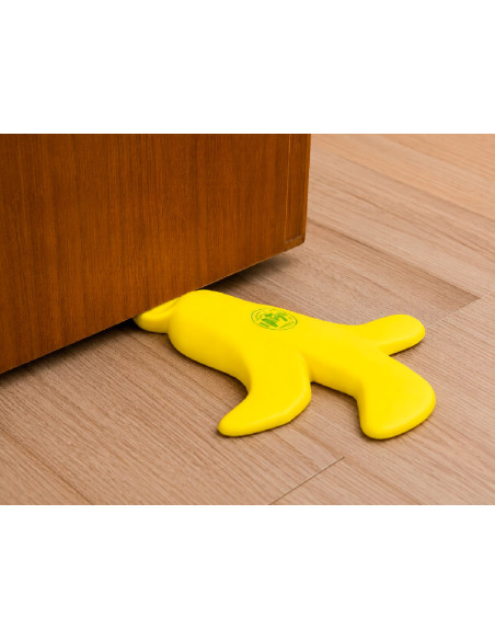 Sujetapuertas divertido de silicona con forma de platano amarillo chafado debajo de una puerta en casa