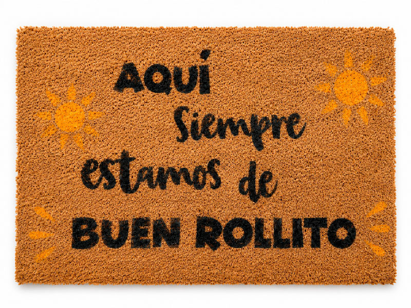 Felpudo de fibra de coco decorado con la frase Aqui siempre estamos de buen rollito y dos soles dibujados a los lados