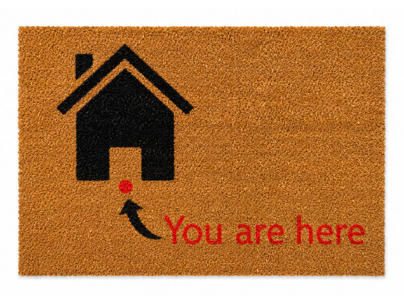 Felpudo de fibra de coco con el diseño de un mapa virtual que muestra una casita negra y el pin rojo con el texto You are here
