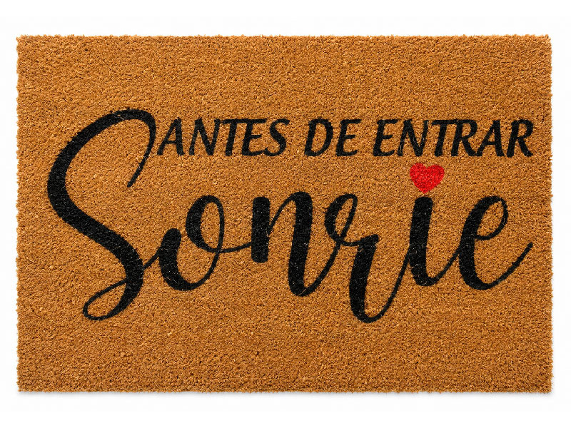 Felpudo de fibra de coco natural con la frase manuscrita Antes de entrar, sonrie decorado con un pequeño corazon rojo