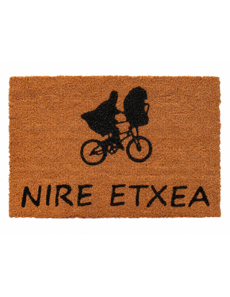 Felpudo de fibra de coco con la silueta negra de E.T. y Elliot volando en bicicleta frente a la luna y la frase Nire Etxea